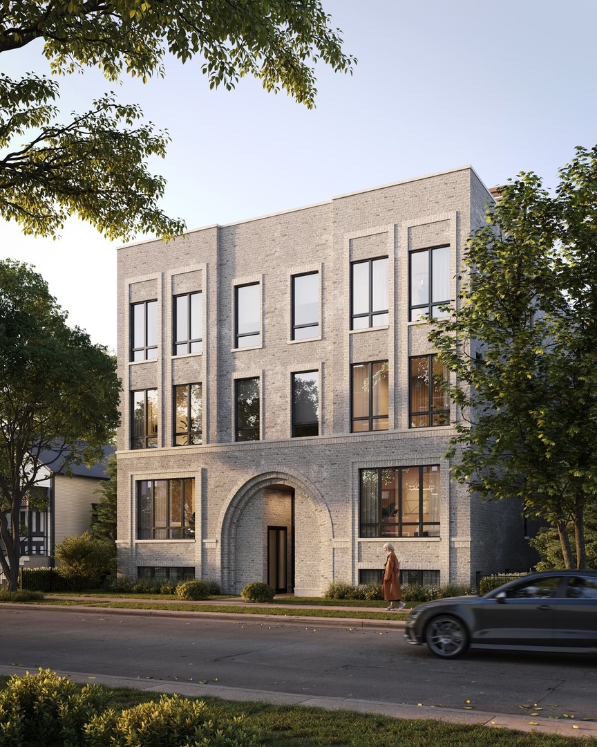 Three-story gray-brick building with tall black-framed windows and a prominent arched entrance.