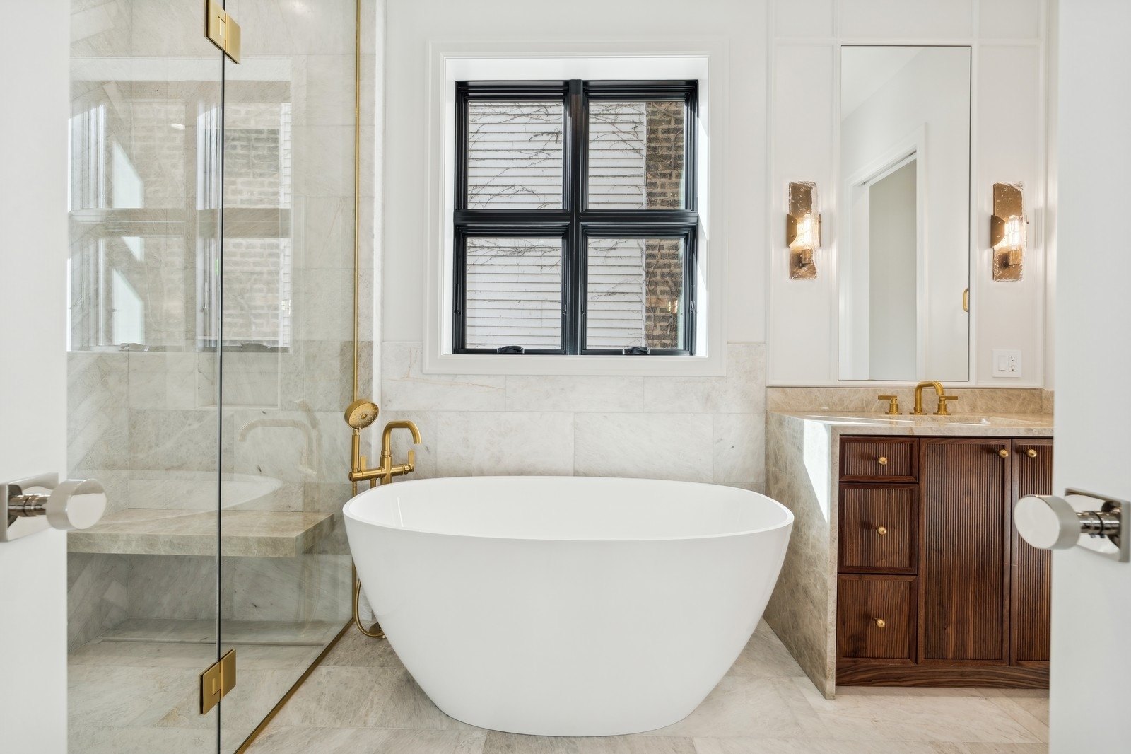 Marble bathroom with a freestanding soaking tub, glass shower, and dark wood vanity.