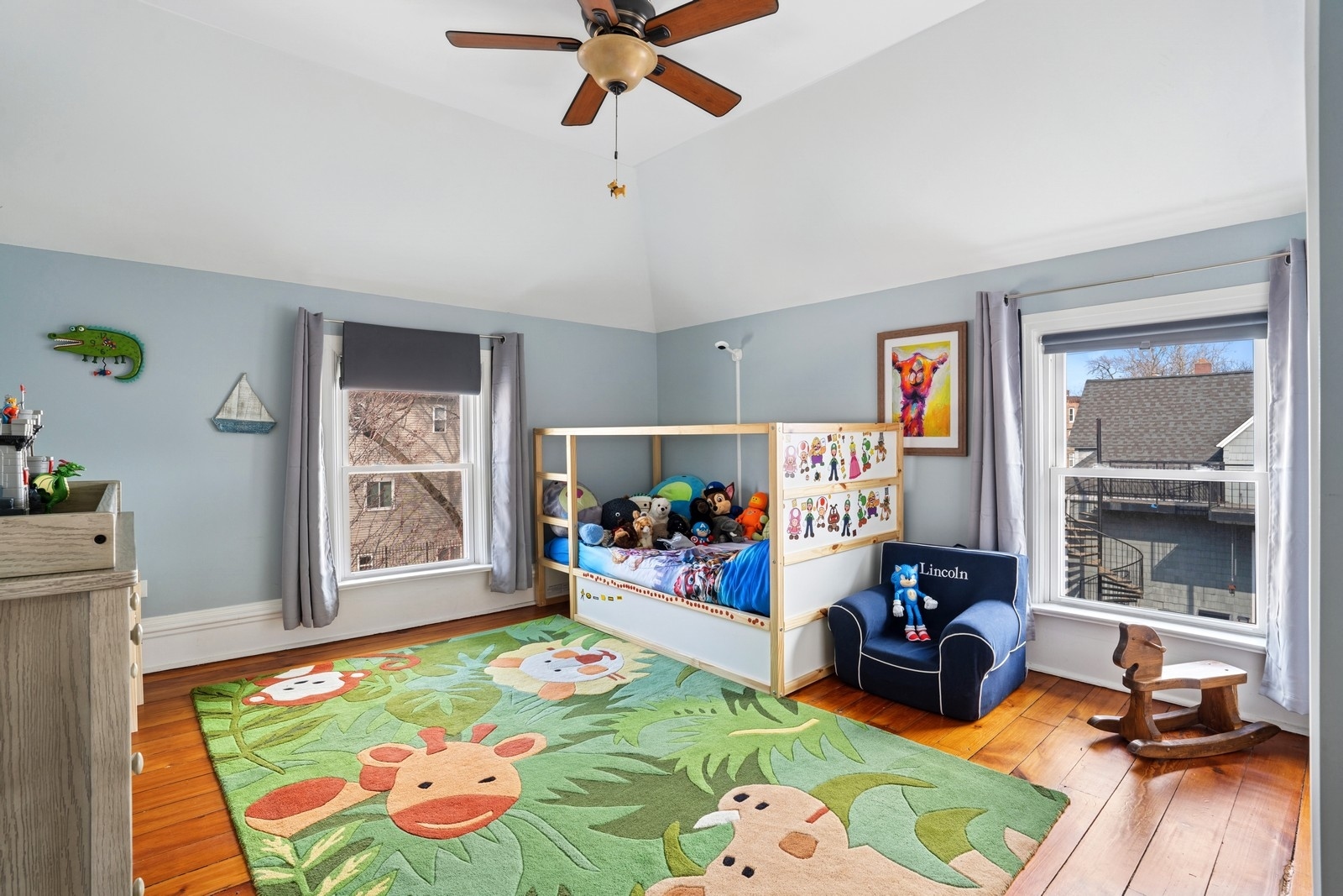 Children’s bedroom with a stuffed-animal bunk bed, green animal rug, and hardwood floors.