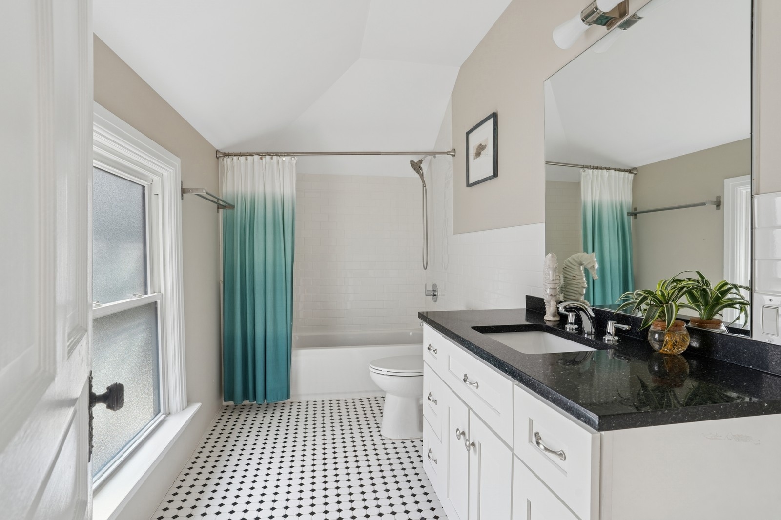 Bathroom with a teal ombré shower curtain, patterned floor, and white vanity with black countertop.