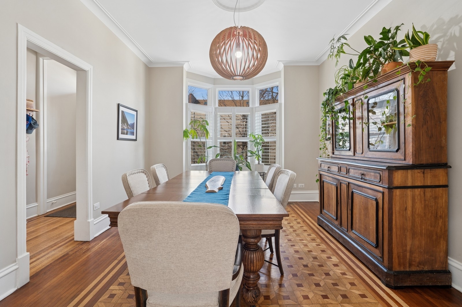 Dining room with parquet floors, a bay window, and a large wooden china cabinet.