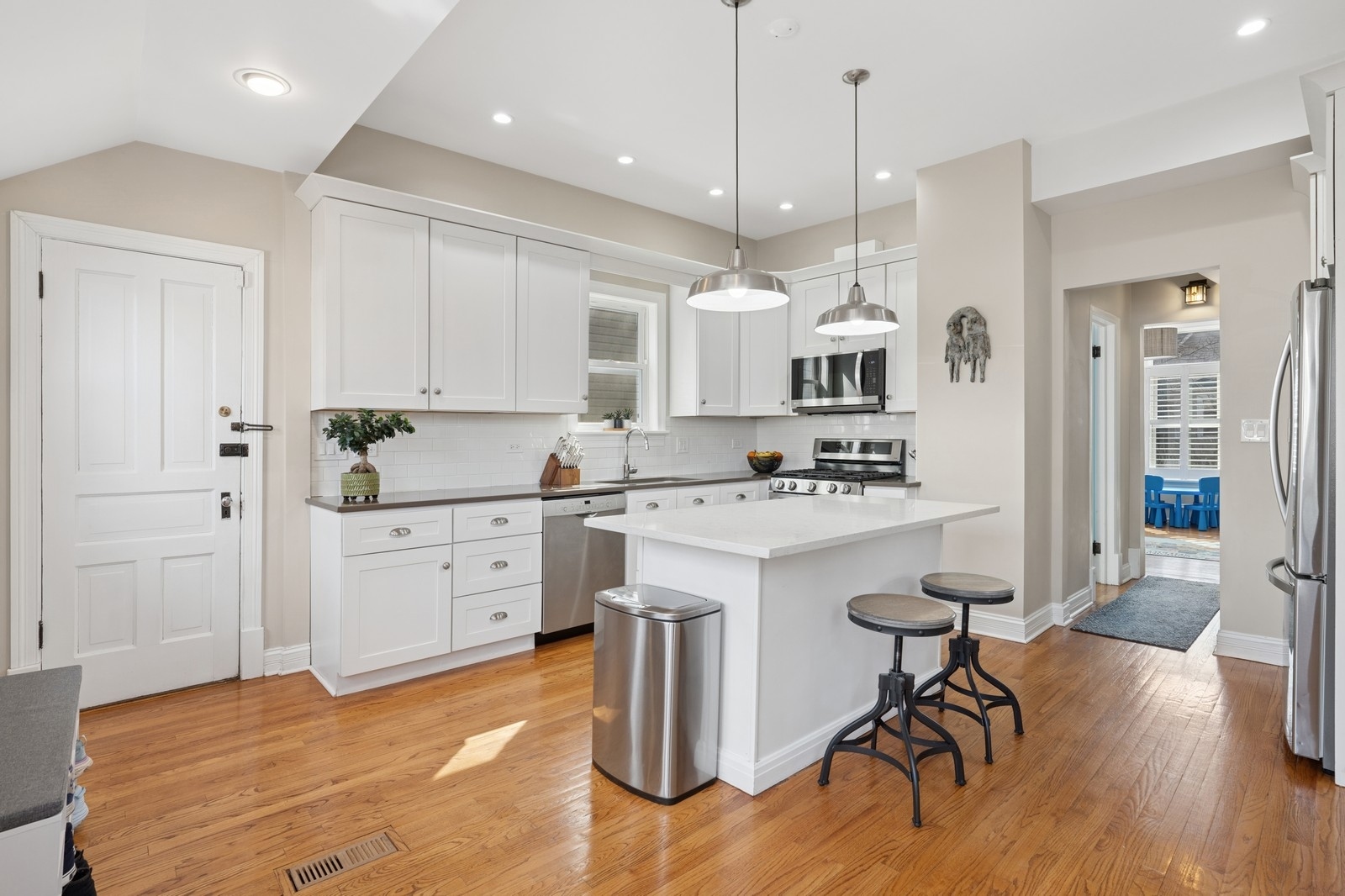 Kitchen with white cabinets, stainless steel appliances, and a large island with two stools.