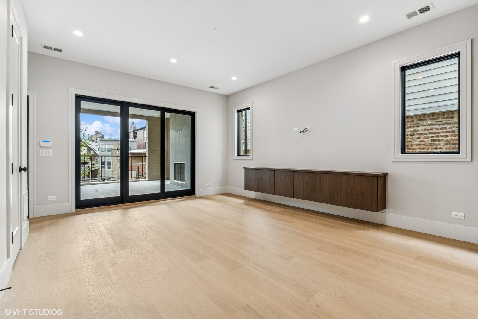Unfurnished living room with pale wood floors and sliding glass doors to a balcony.