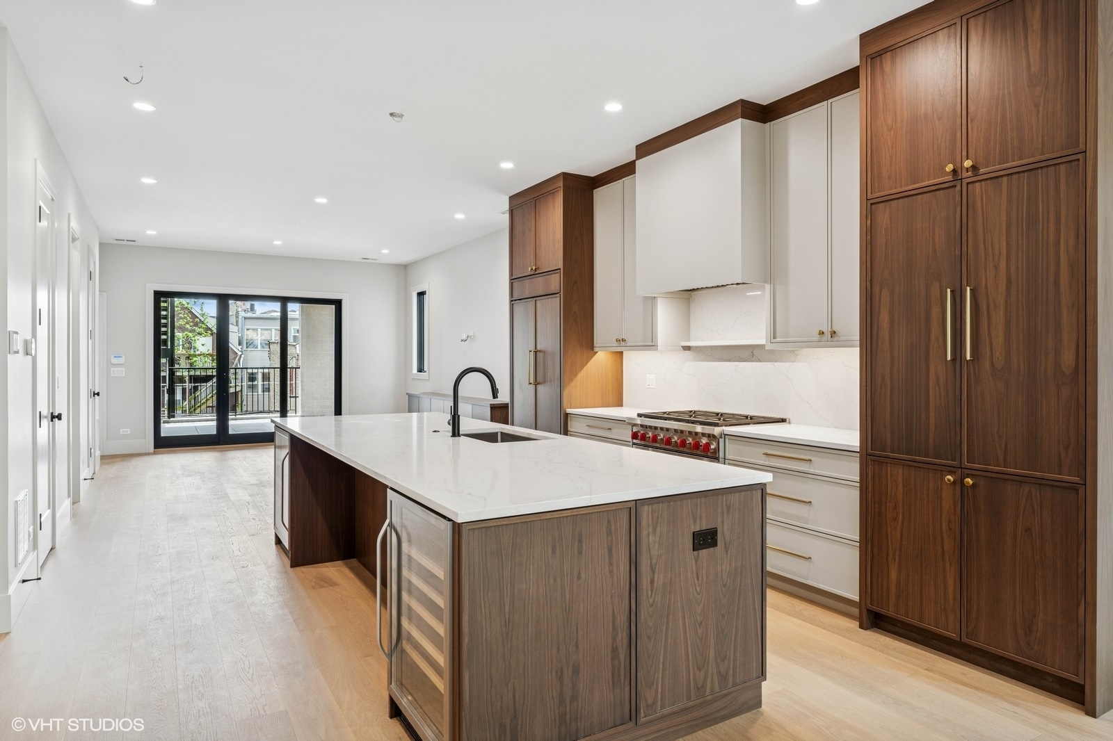 Kitchen with a large stone island, dark wood cabinetry, and sliding doors to a balcony.
