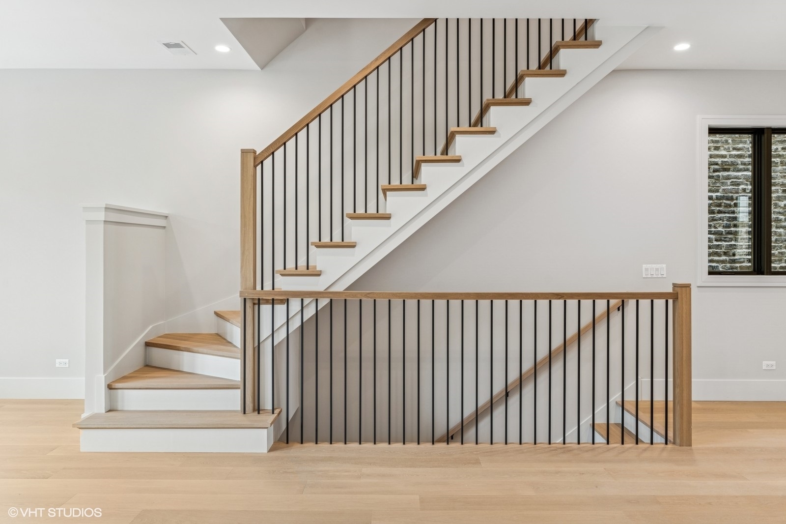 Interior staircase with light wood treads and black metal railings.