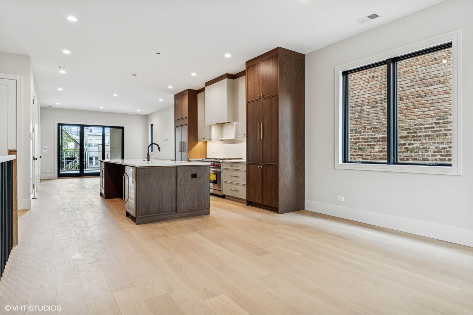 Open kitchen with dark wood cabinetry, a large island, and light hardwood floors.
