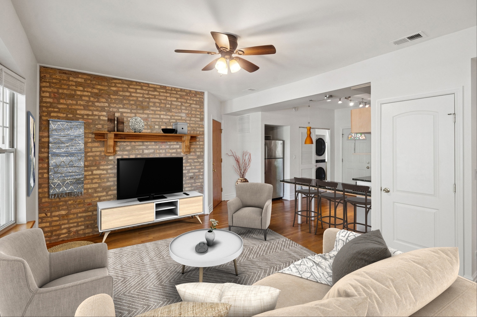 Living room with exposed brick accent wall, hardwood floors, and adjoining dining area.