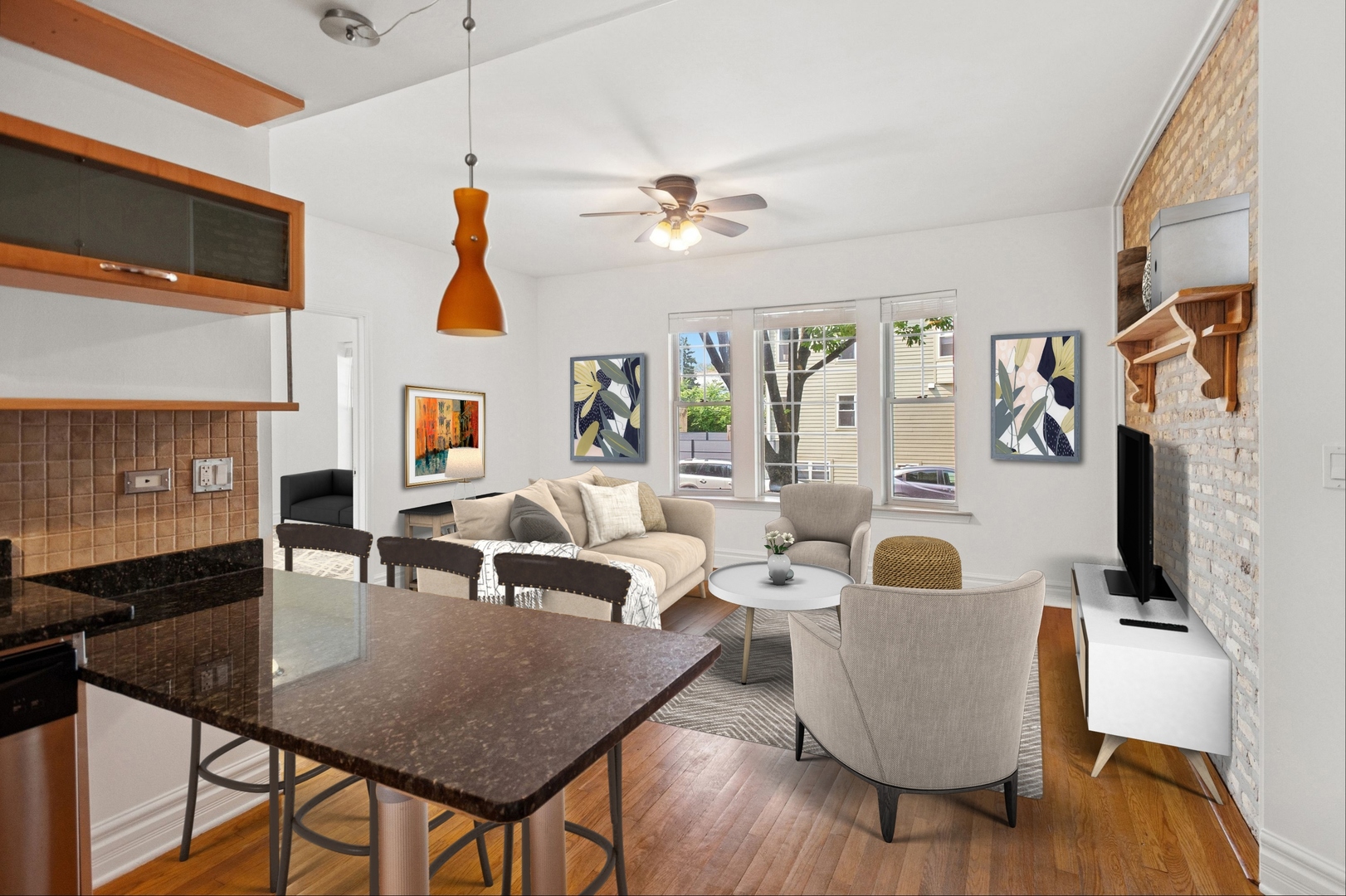 Open-plan living room with hardwood floors, a stone breakfast bar, and an exposed white brick wall.