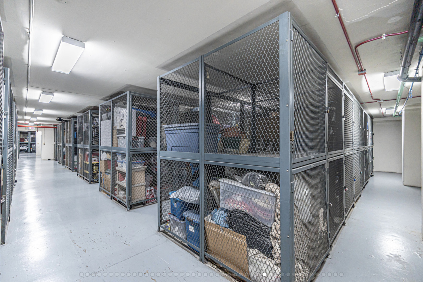 Condominium storage room with rows of mesh cages filled with household belongings.