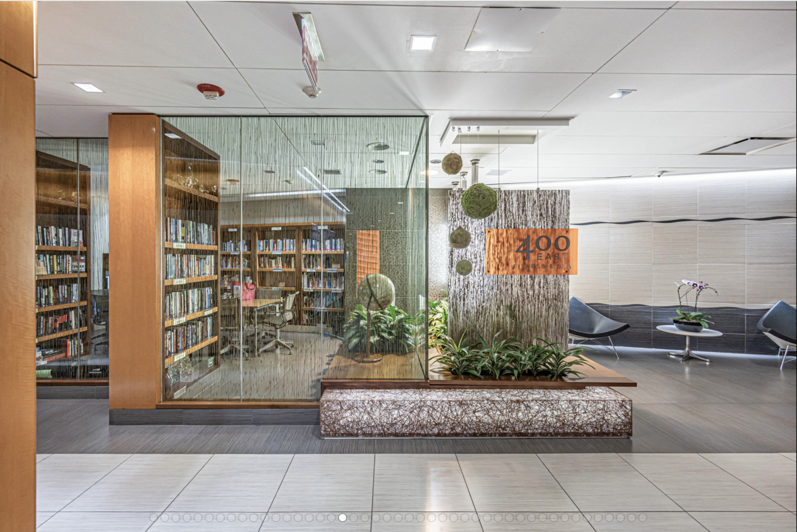 Building amenity lobby with a glass-enclosed library, lounge seating, and a 400 East Fitness & Spa sign.