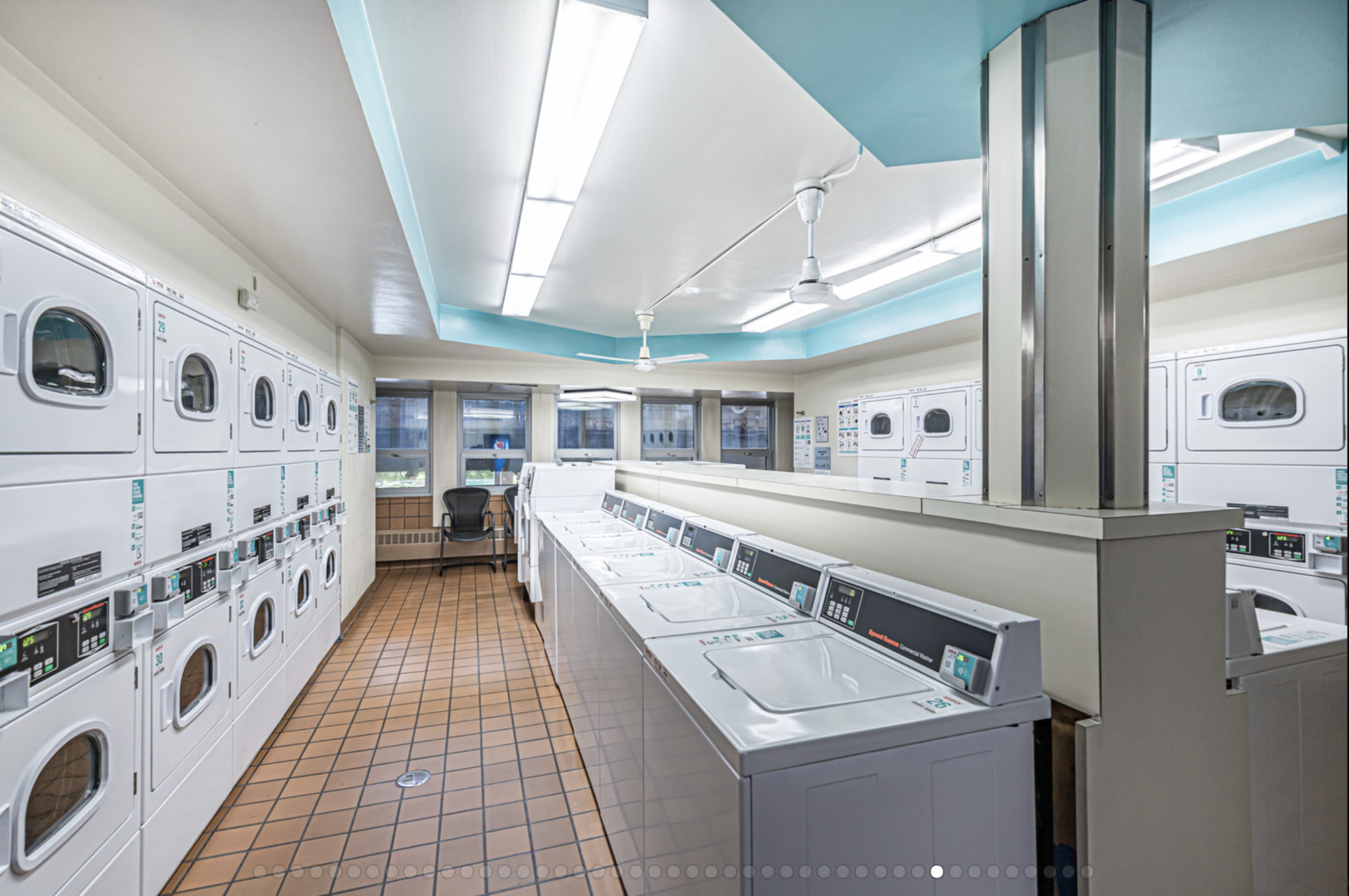 Community laundry room with rows of washers and dryers and turquoise ceiling accents.