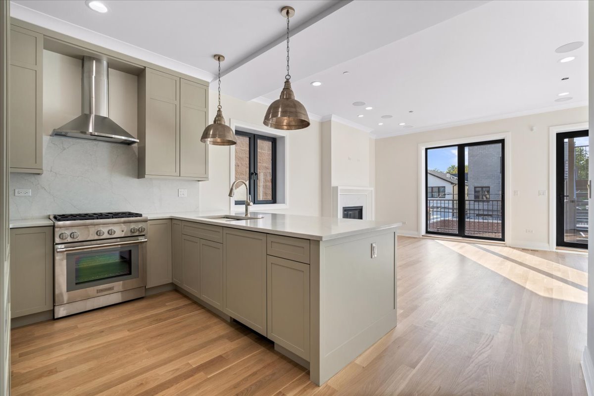 Open-plan kitchen with a large island, stainless steel range, and balcony doors.