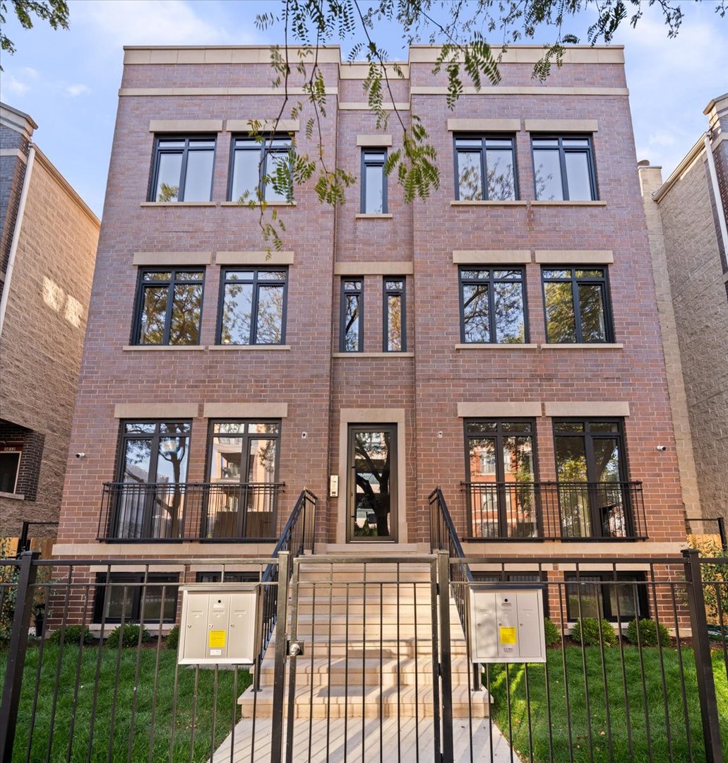 Brick residential building with a central stone staircase, black railings, and small front balconies.