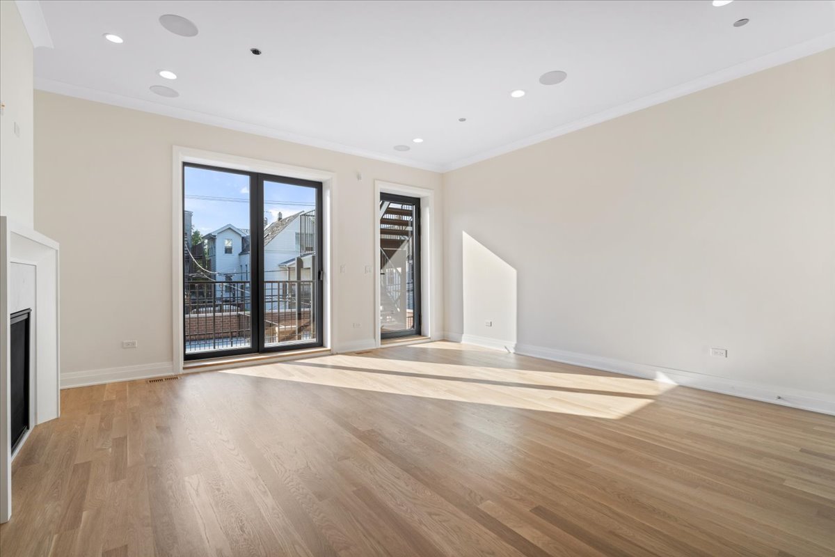 Empty living room with light wood floors, a fireplace, and glass balcony doors.