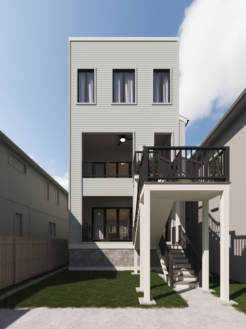 Rear of a multi-story home with a raised deck, exterior stairs, and fenced lawn.