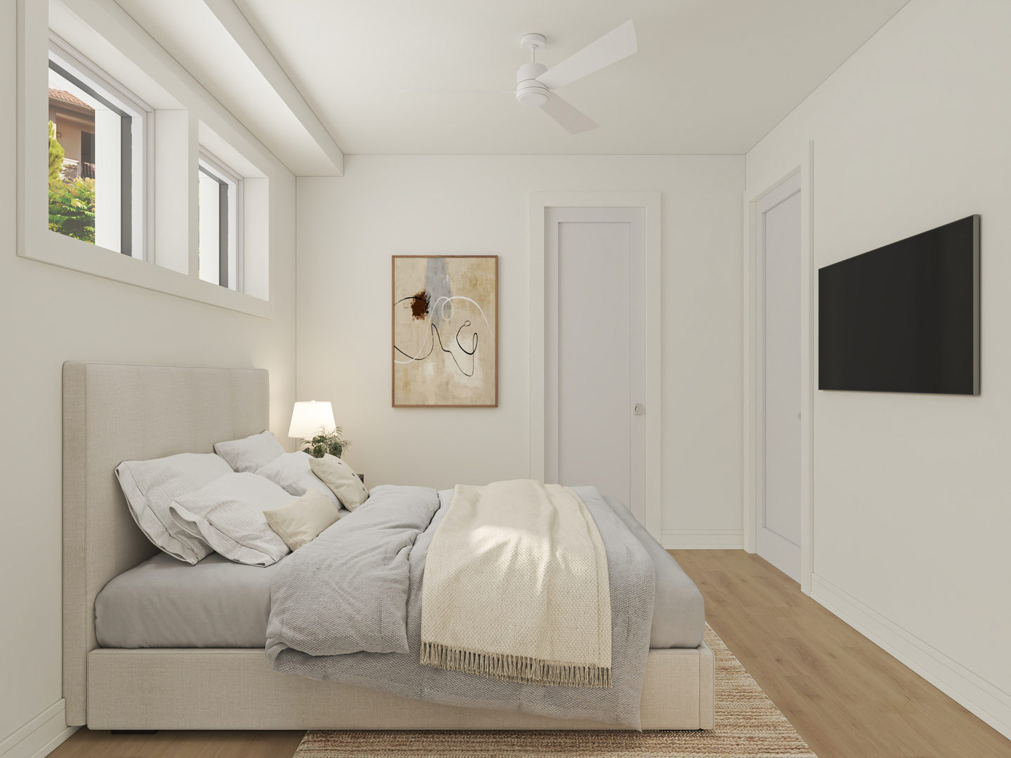 Furnished bedroom with a gray upholstered bed, high windows, and a wall-mounted television.