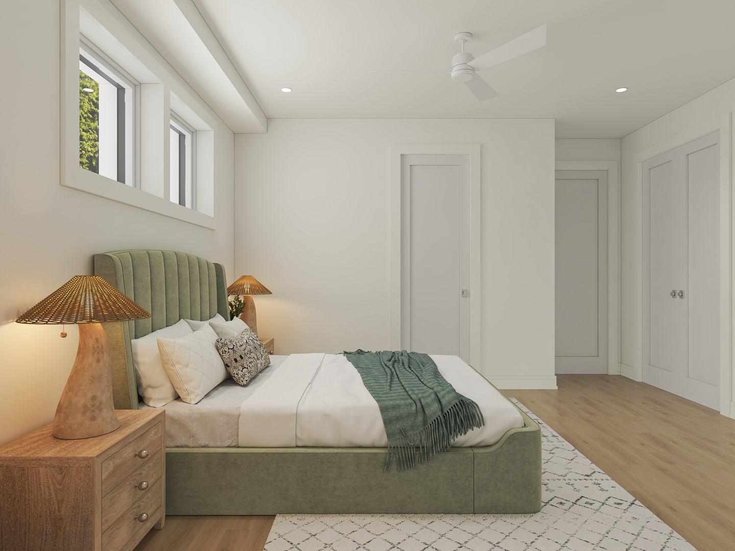 Staged bedroom with a green upholstered bed, patterned rug, and high windows.