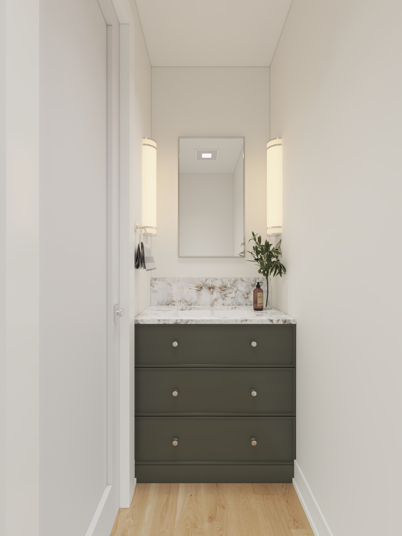 Bathroom vanity with dark green drawers, marble countertop, mirror, and vertical wall sconces.