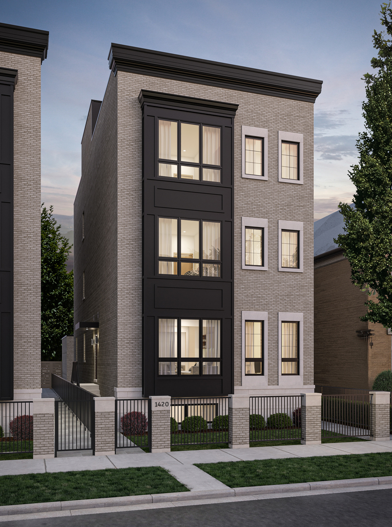 Multi-story brick residence with a dark window bay, illuminated windows, and a gated front fence.