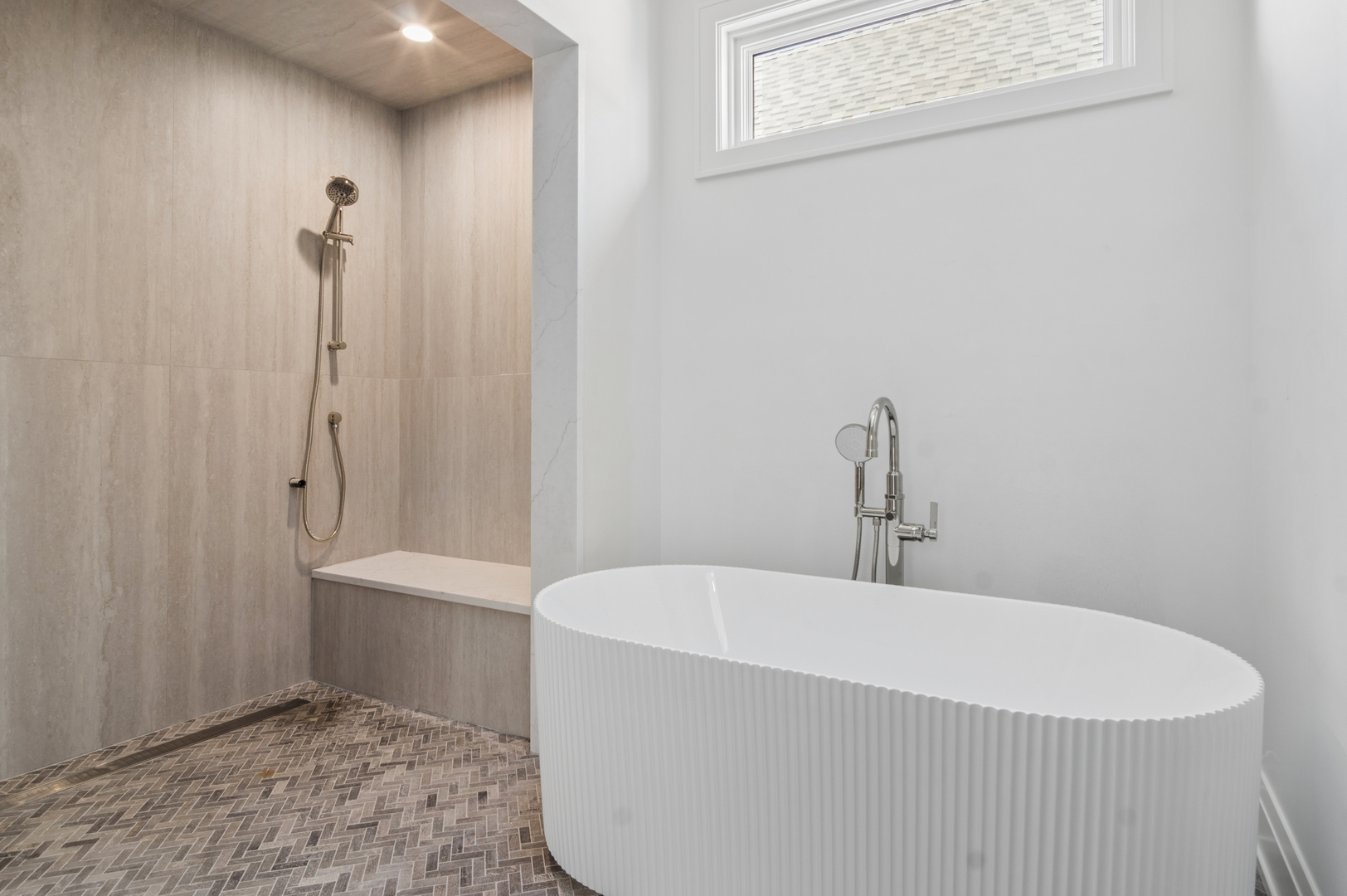 Modern bathroom with a fluted freestanding tub, tiled walk-in shower, and built-in bench.