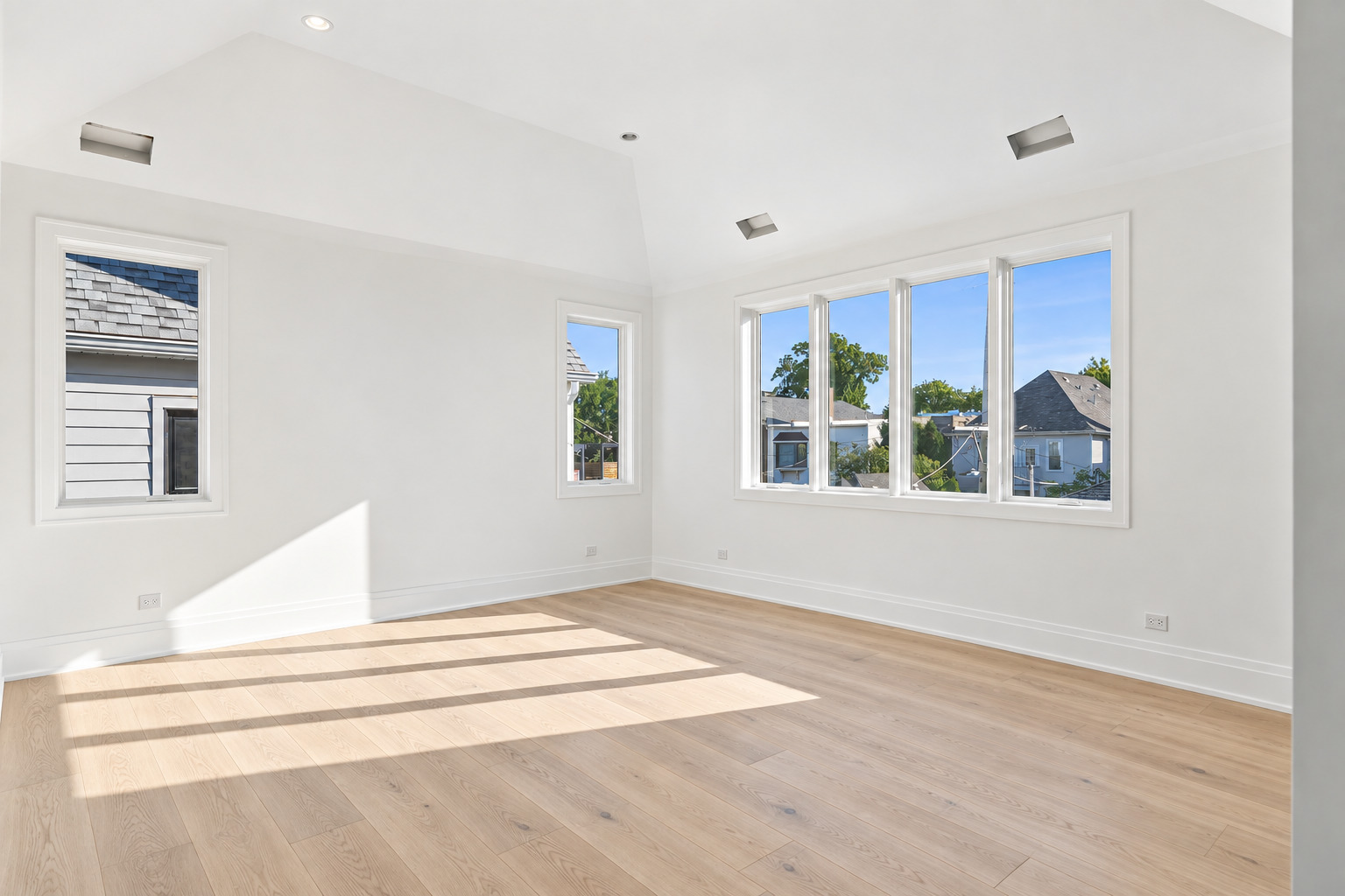 Vacant room with light hardwood floors, a high ceiling, and large windows.