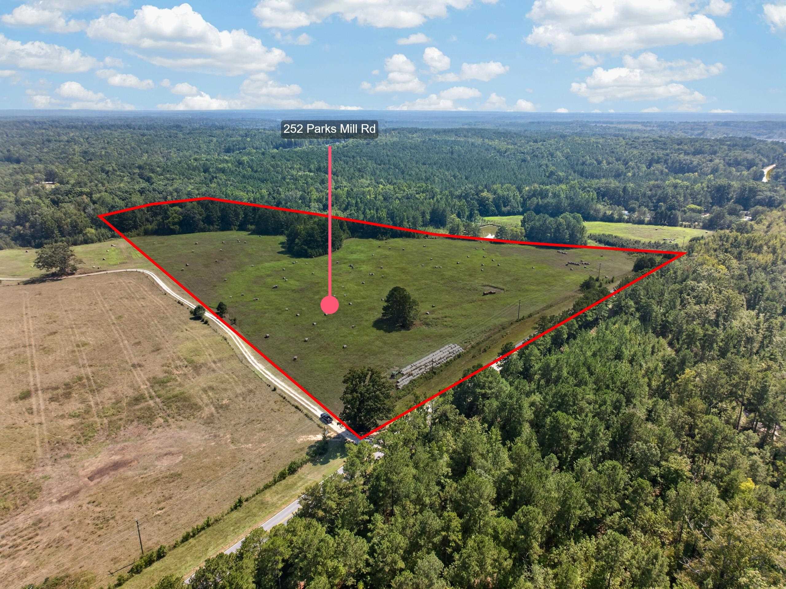 Aerial view of pasture land outlined in red, with hay bales and surrounding woods.