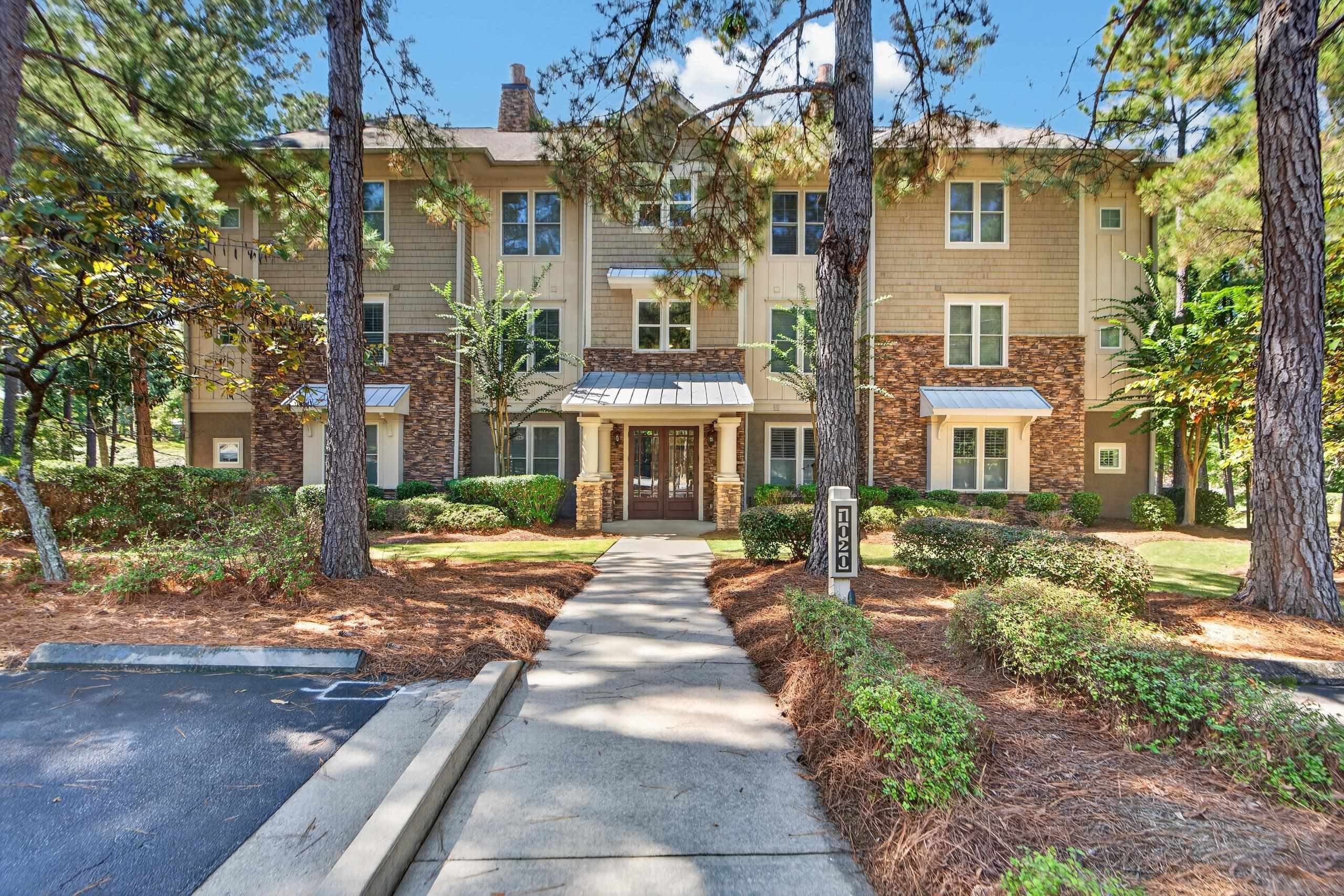Multi-unit residence with stone accents and a walkway leading to its central entrance.