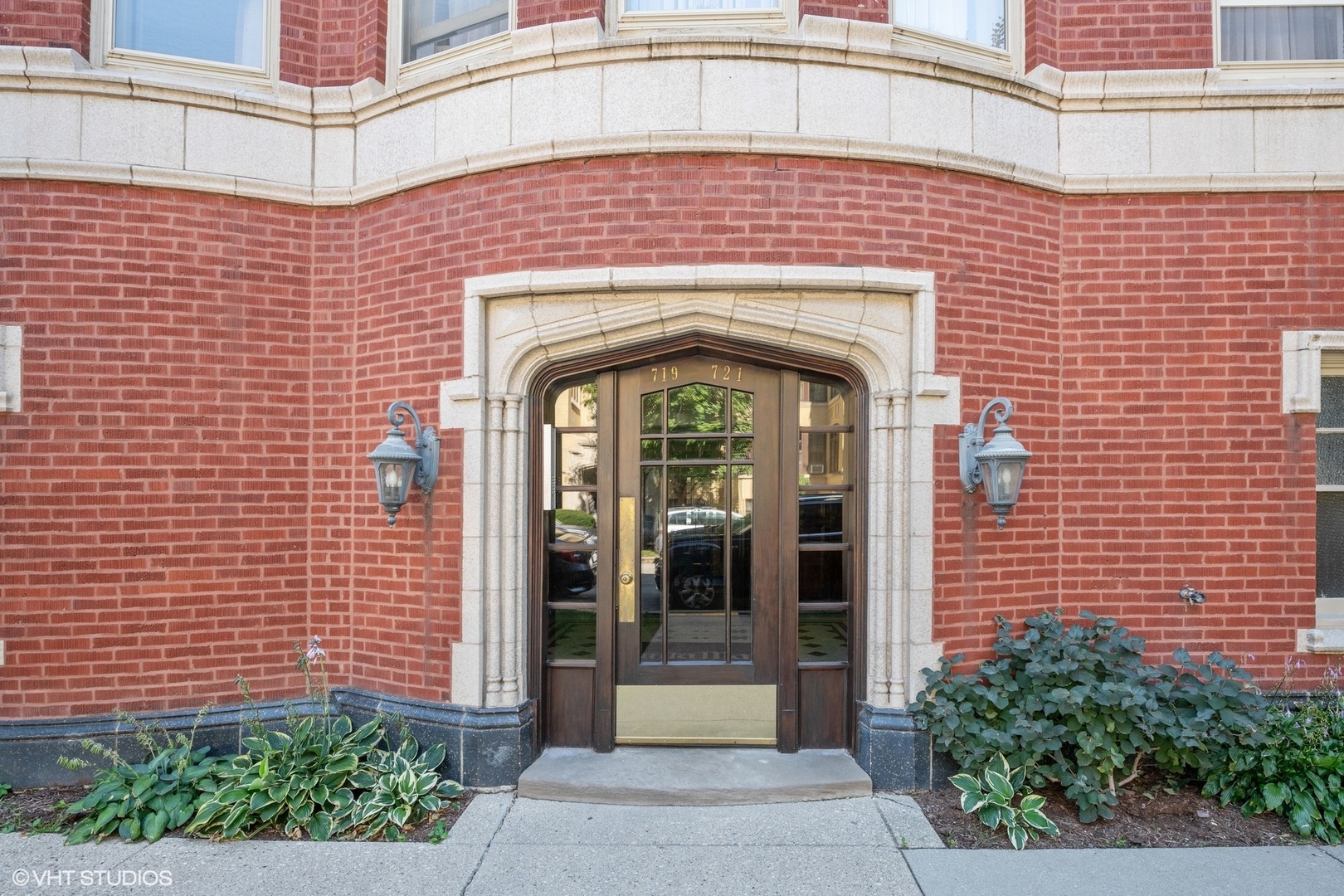 Red-brick building entrance with an ornate stone arch and dark glass door marked 719 and 721.