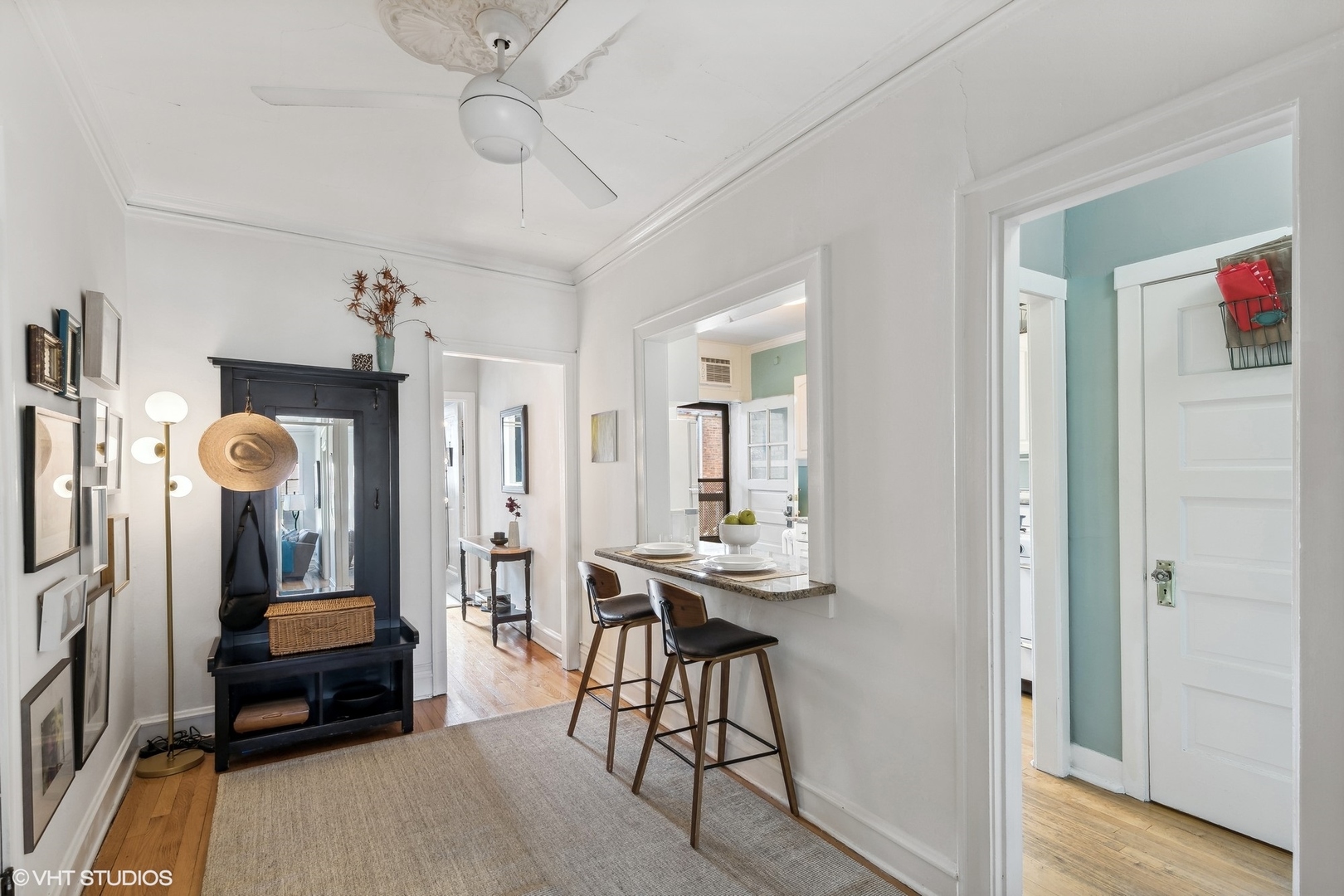 Apartment entry hall with a black built-in hall tree and a granite breakfast bar with two stools.