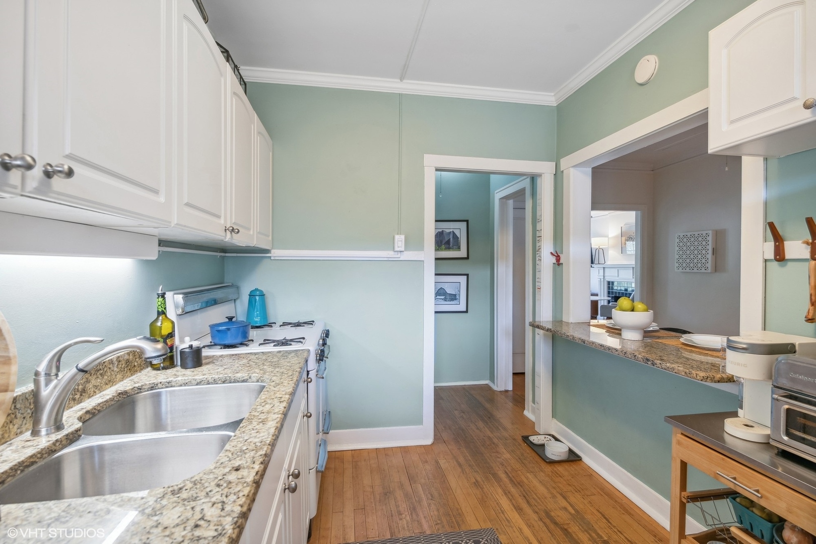 Kitchen with pale green walls, granite counters, a double sink, and a pass-through counter.