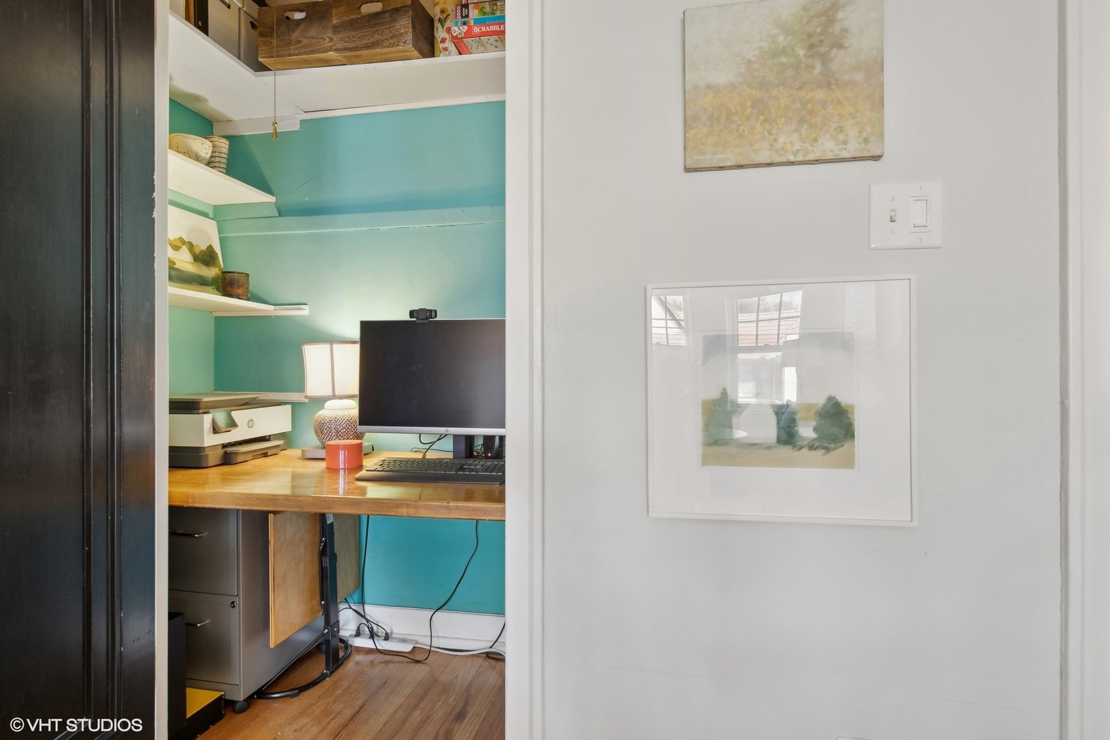Home office nook with turquoise walls, wooden desk, computer, and printer.
