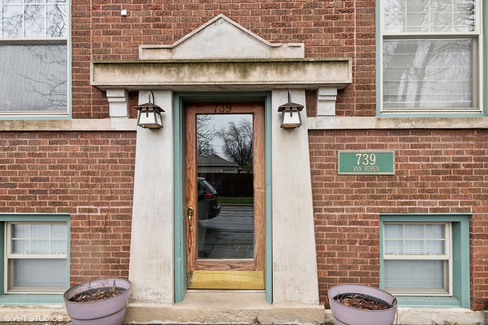 Brick building entrance with a stone doorway, wood-and-glass door, lanterns, and 739 Van Buren plaque.