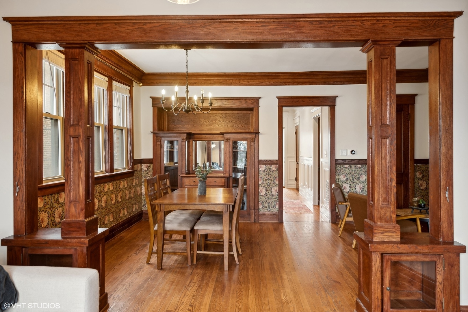 Dining room with ornate wood trim, built-in cabinet, hardwood floors, and chandelier.