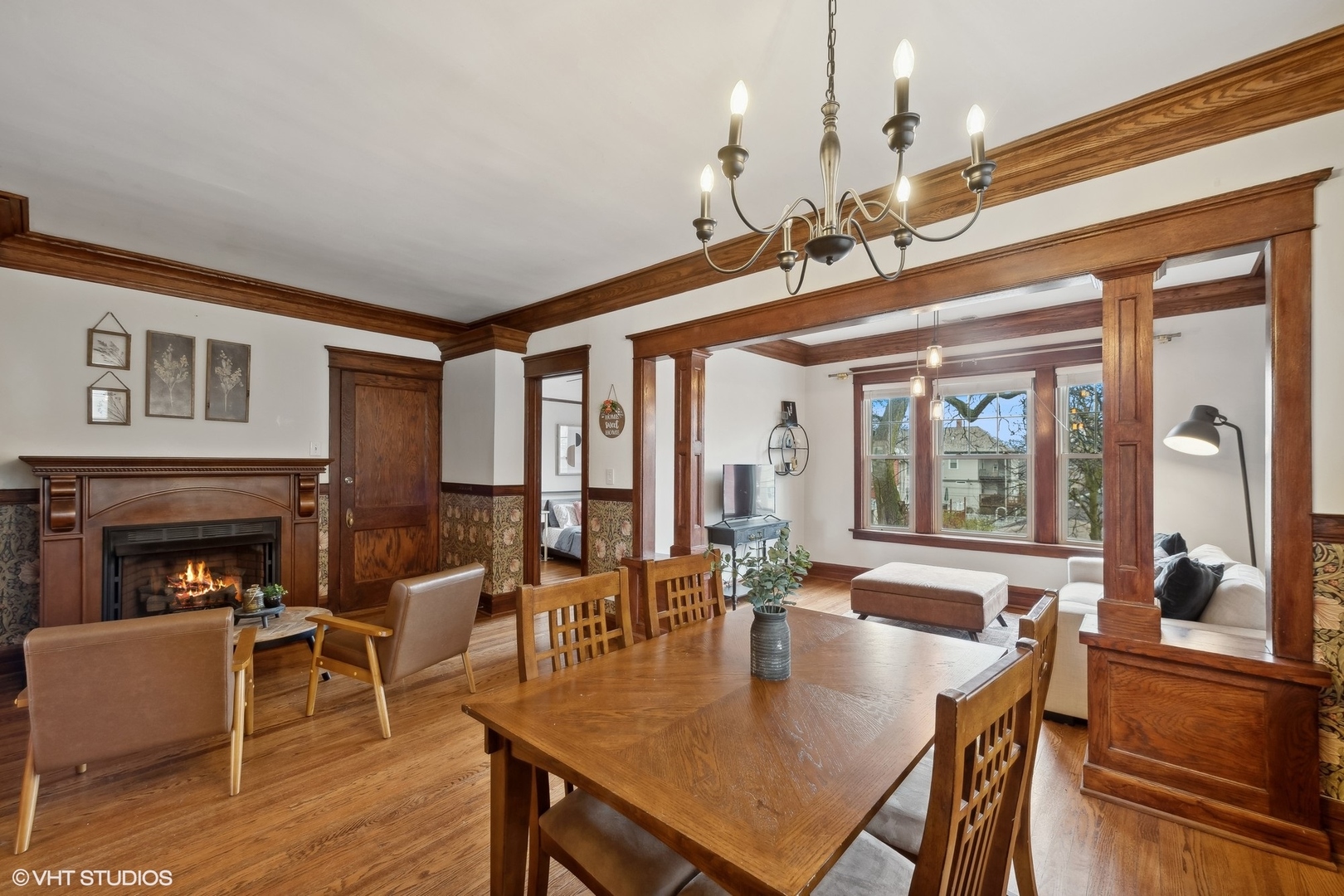 Dining room with ornate wood trim, a lit fireplace, and an open connection to the living area.