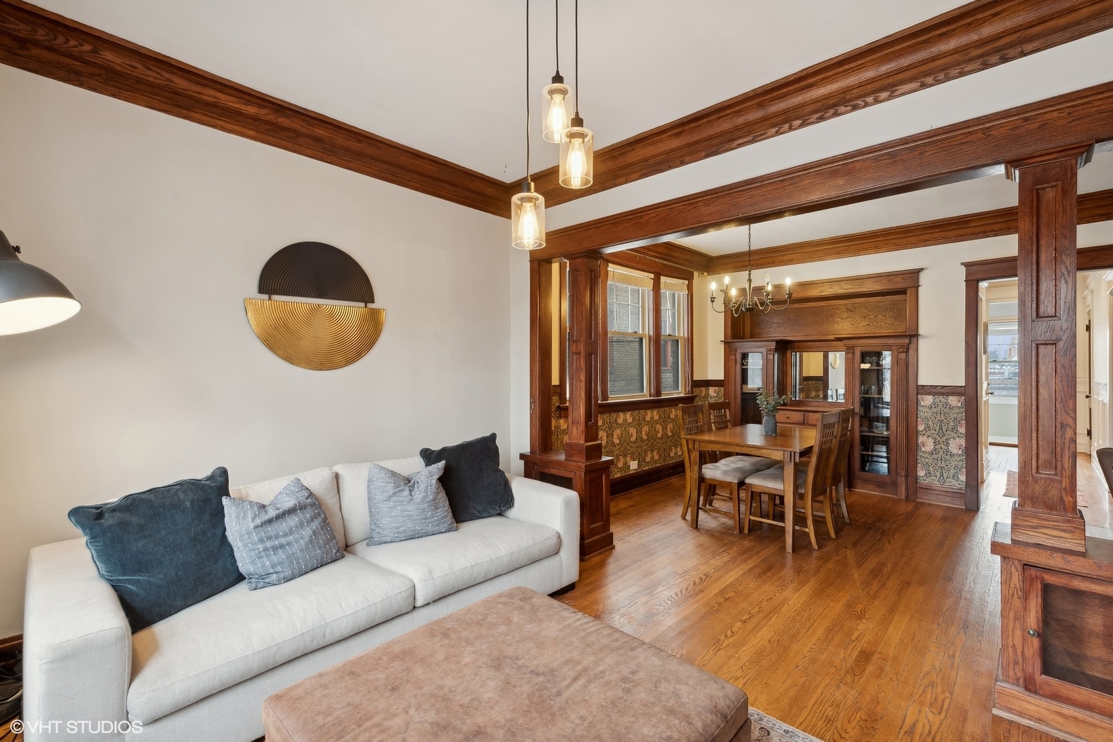 Living and dining room with dark wood beams, built-in cabinetry, hardwood floors, and a white sofa.