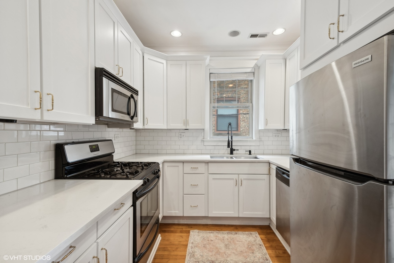 Renovated kitchen with white cabinetry, stainless steel appliances, a black gas range, and a window above the sink.
