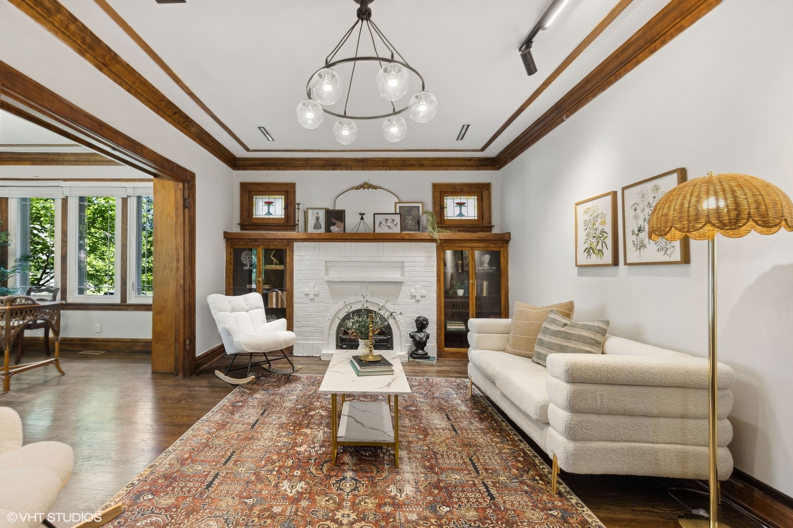 Living room with a white brick fireplace, exposed wood beams, and a patterned rug.