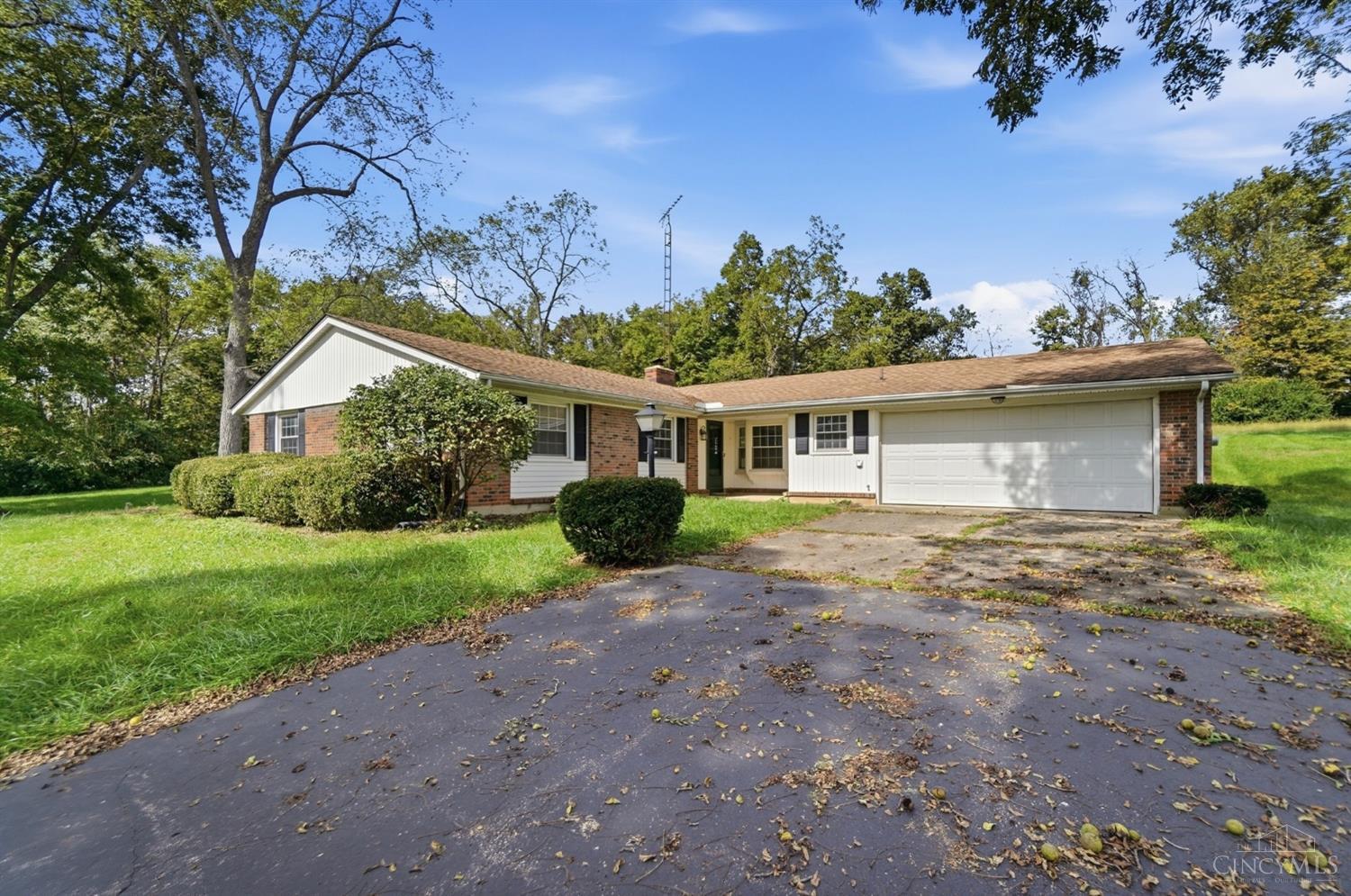 Single-story brick-and-siding ranch home with a two-car garage and mature trees.
