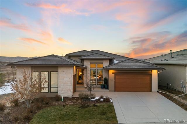 Contemporary home with a stone facade and attached garage beneath a colorful sunset sky.