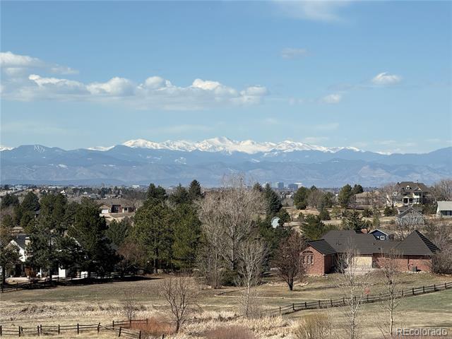 Colorado homes and open fields with snowcapped Rocky Mountains in the distance.