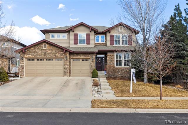 Two-story stone-and-siding home with a two-car garage, broad driveway, and leafless trees.