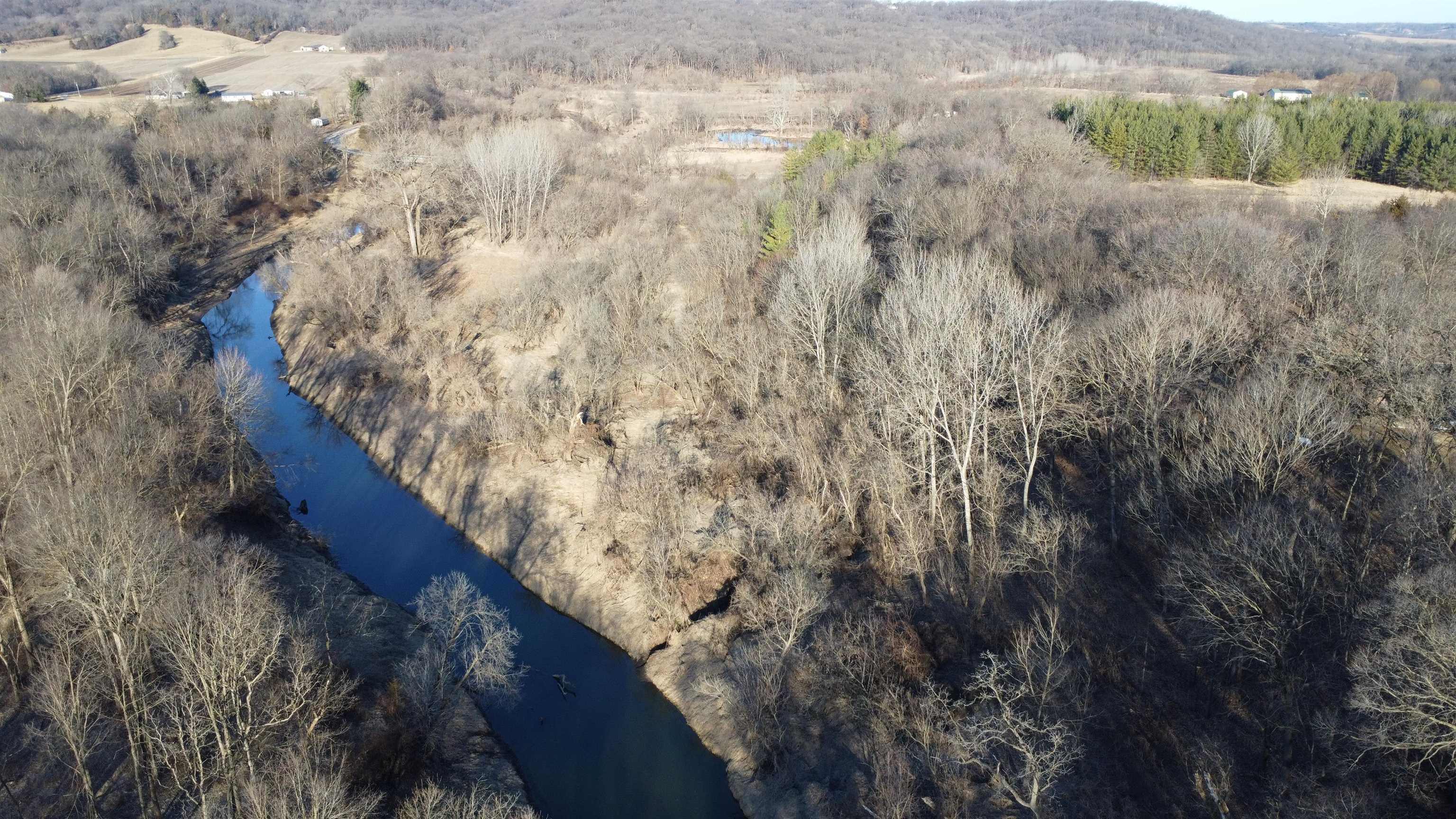 Wooded acreage with a winding river and open fields.