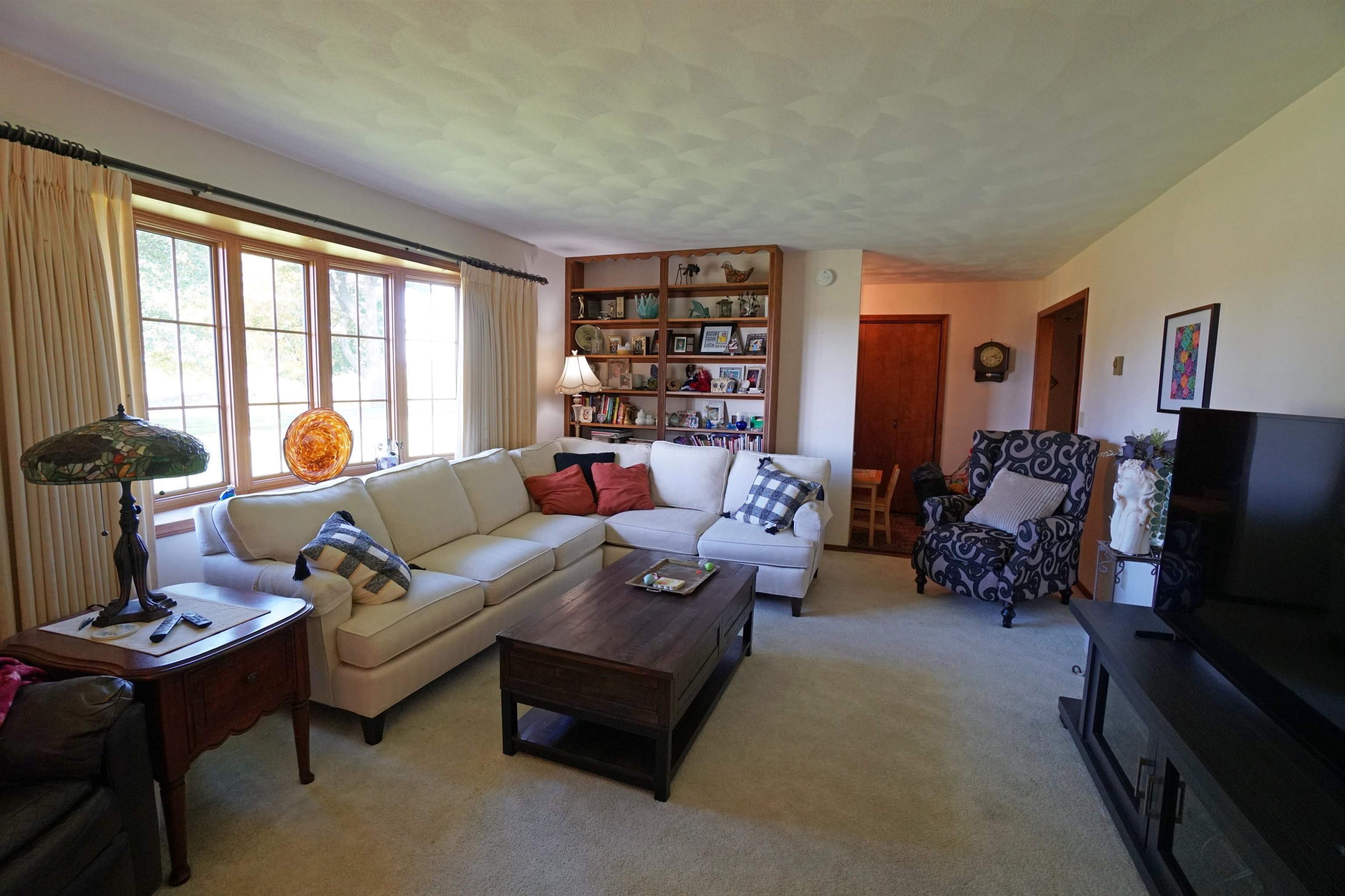 Living room with a cream sectional, built-in bookshelves, and large curtained windows.