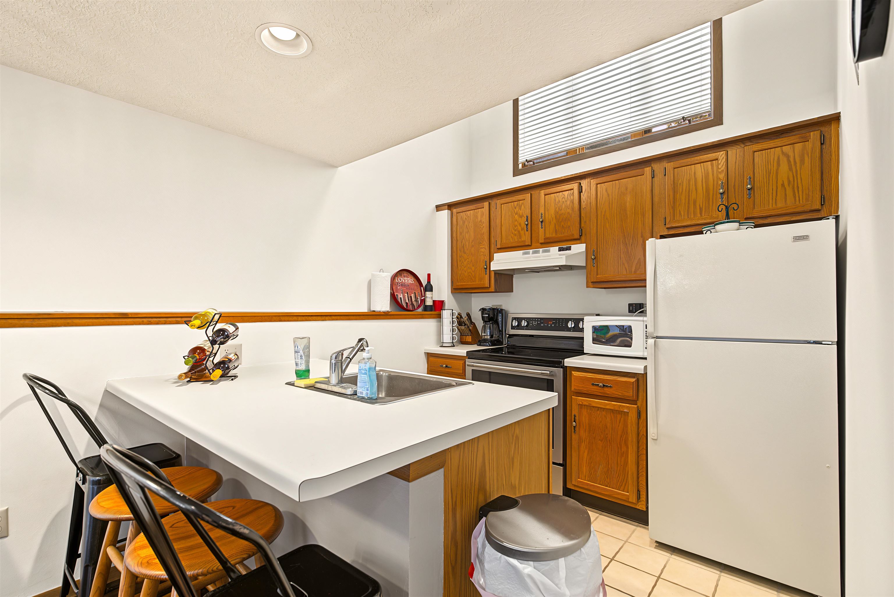Kitchen with warm wood cabinets, white appliances, and a large peninsula with a sink and seating.