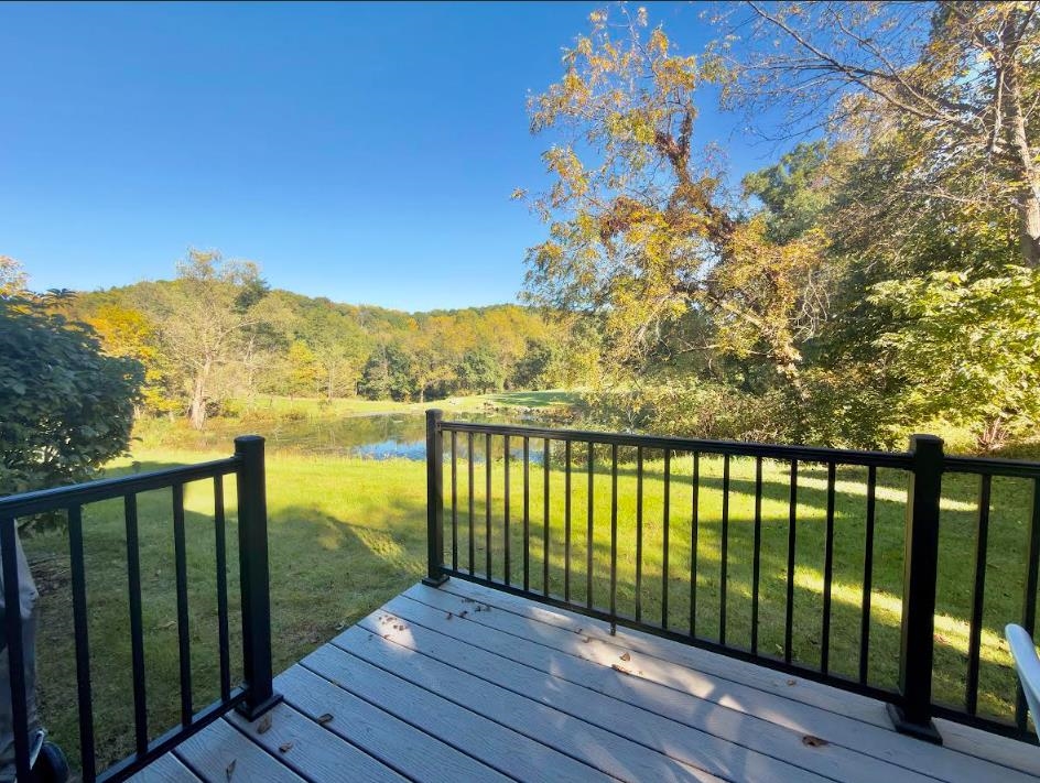 Raised deck overlooks a pond, lawn, and wooded hills with autumn foliage.