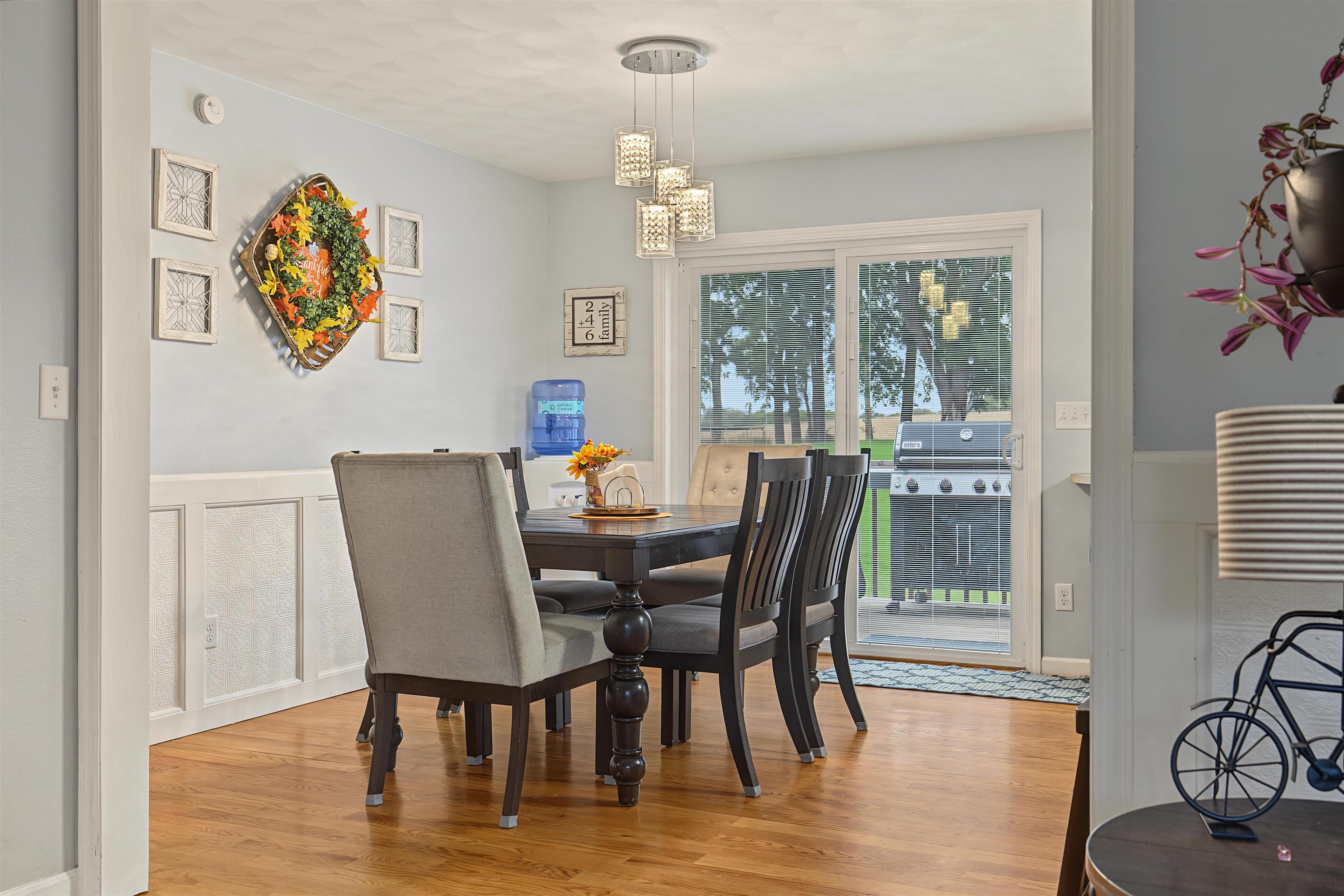Dining room with a dark wood table, upholstered chairs, pendant lights, and sliding glass doors.