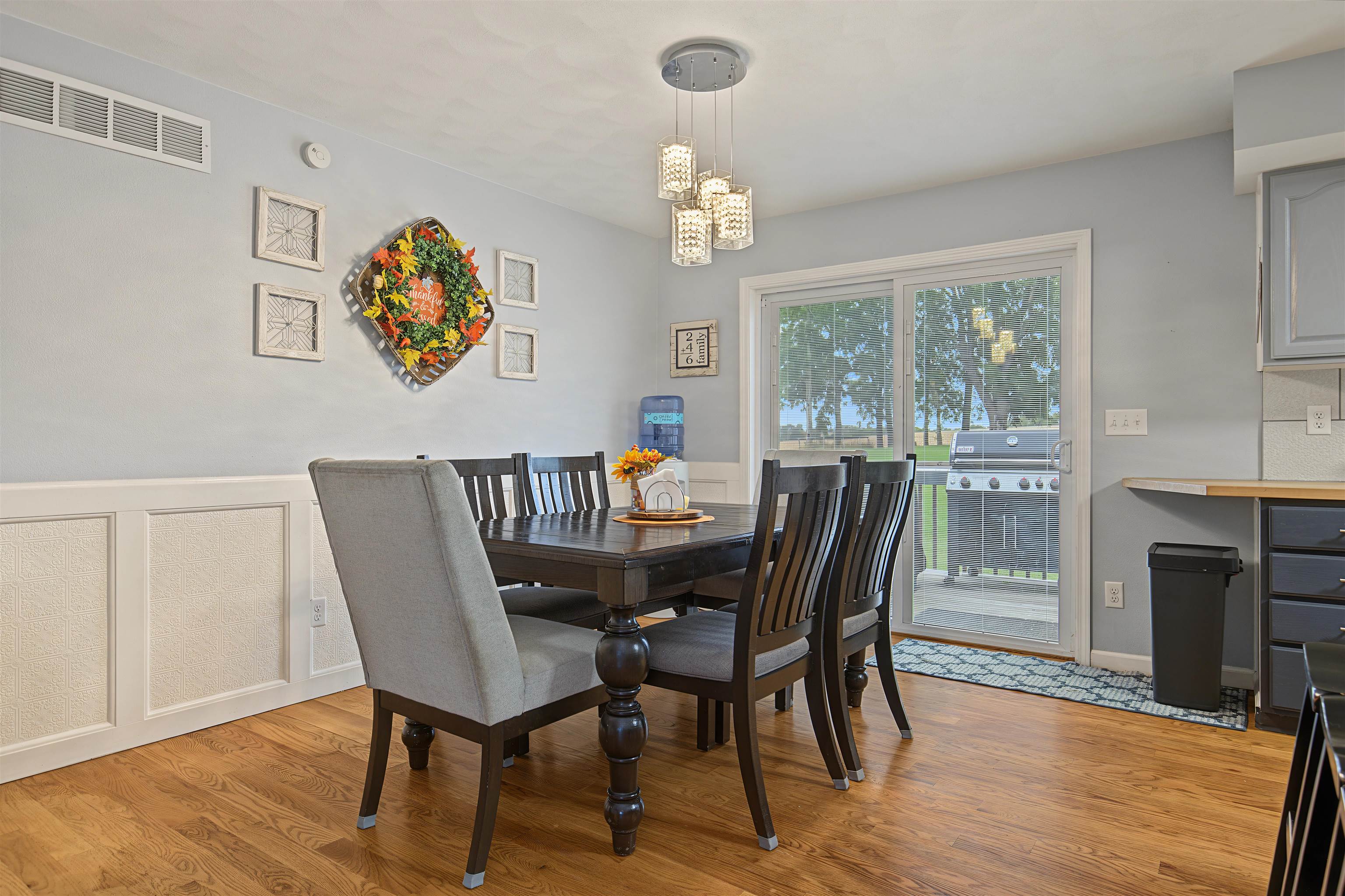 Dining room with a dark wood table, gray upholstered chair, chandelier, and glass patio door.