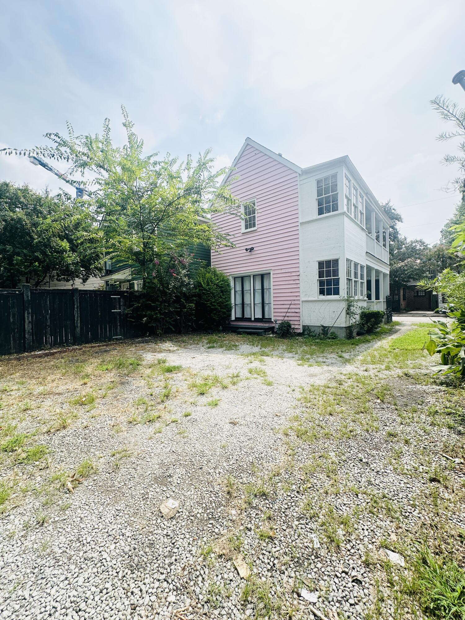 Two-story house with pink and white siding beside a broad gravel yard.