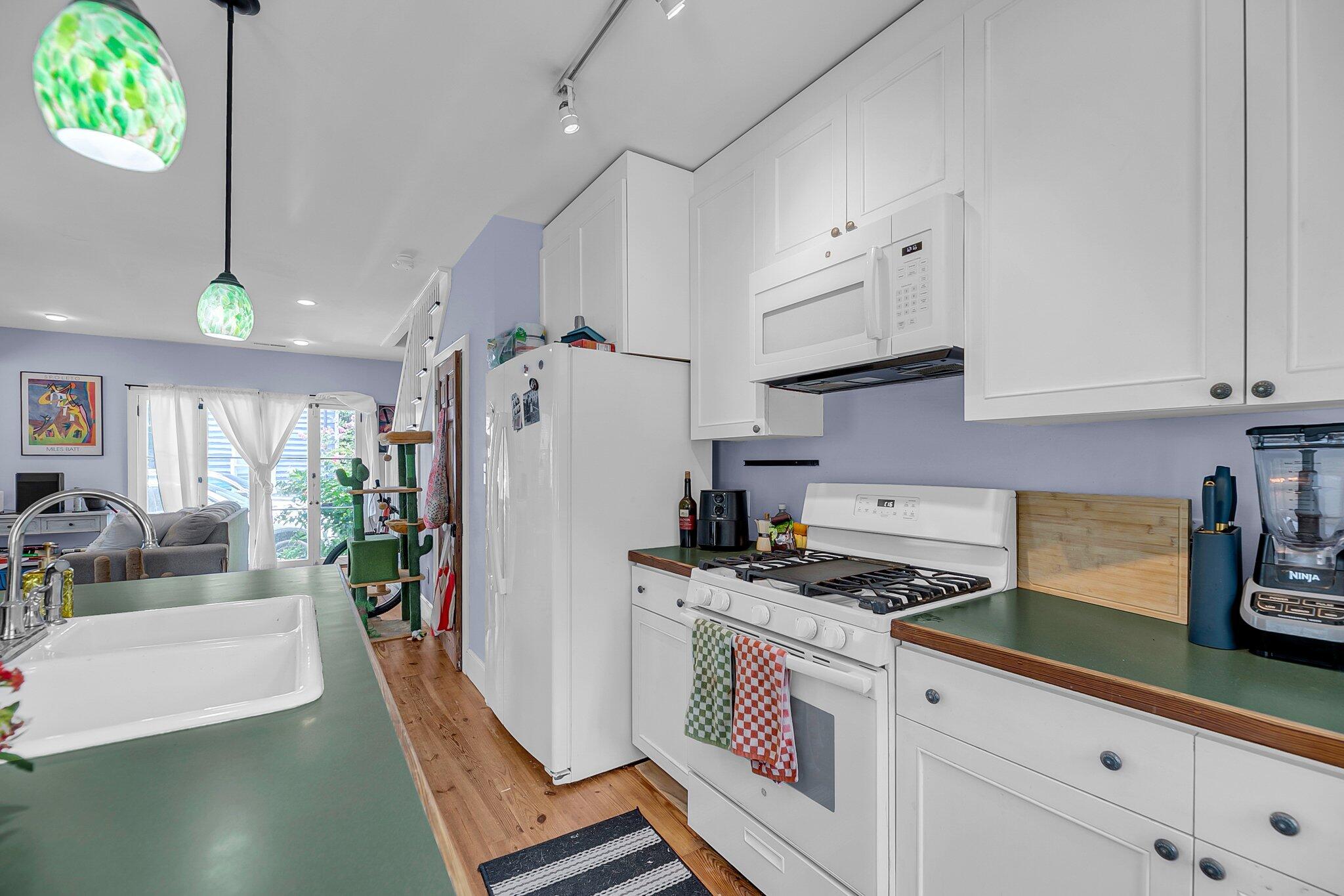 Kitchen with green countertops, white farmhouse sink, gas range, and a view into the living area.