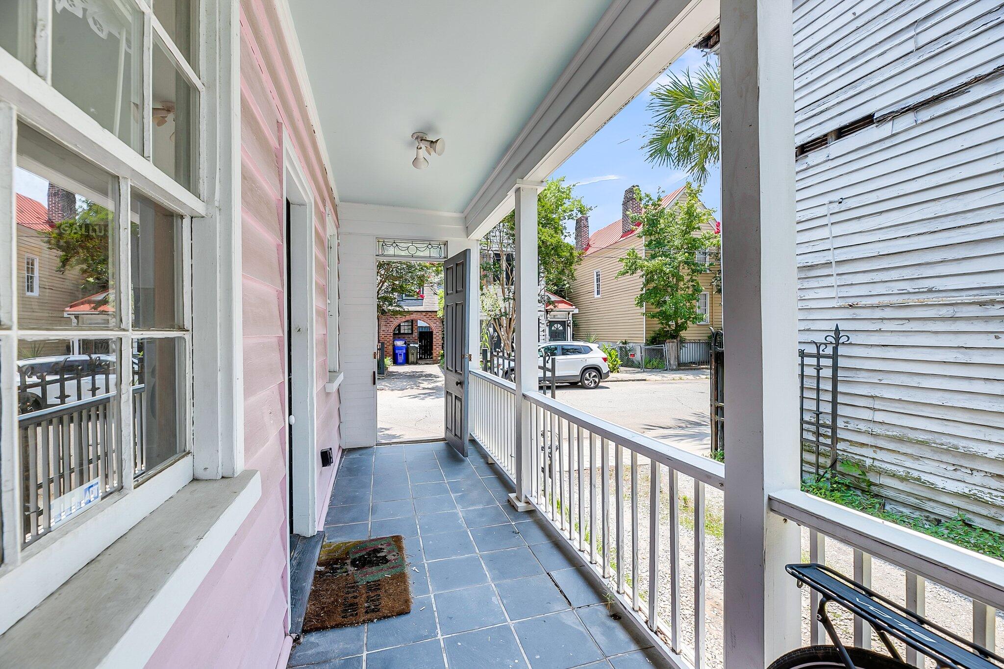 Covered tiled porch with pink siding, white railings, and a view of the residential street.